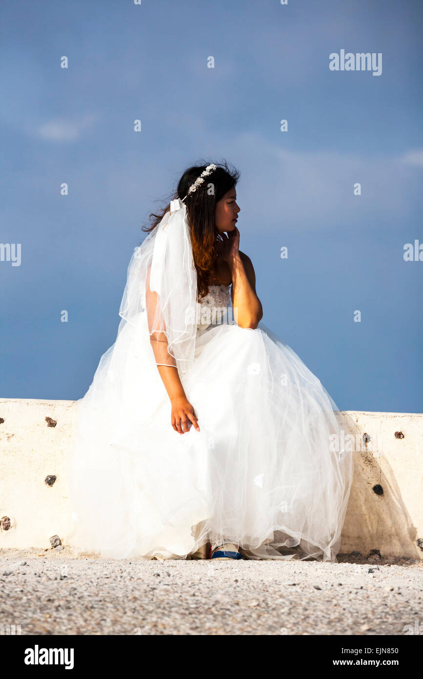 Jeune chinoise portant une robe de mariage traditionnelle et le voile qui pose pour photos avant-mariage, Firostefani, Santorin (Théra), Grèce. Banque D'Images