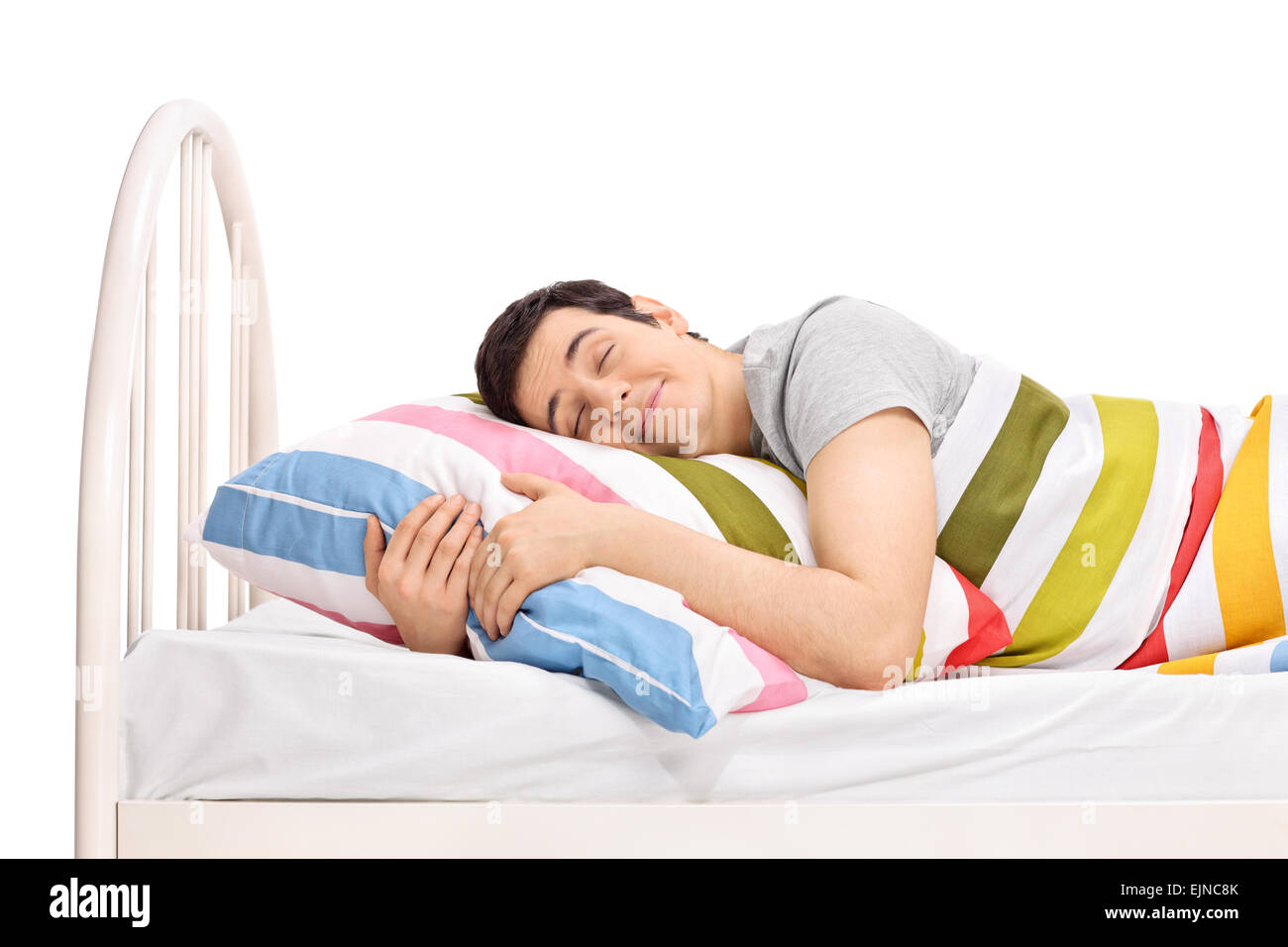 Joyeux jeune homme dormir dans un lit confortable et de rêver de doux rêves recouvert d'une couverture et l'étreindre l'oreiller Banque D'Images