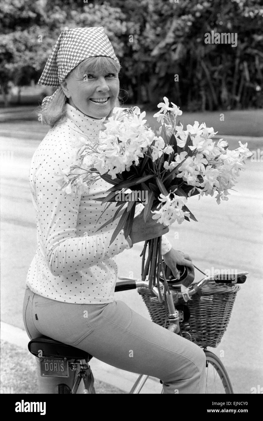 Doris Day vu tenant un bouquet de fleurs sur sa bicyclette, elle roule tous les jours pour garder la forme. Août 1980. Banque D'Images
