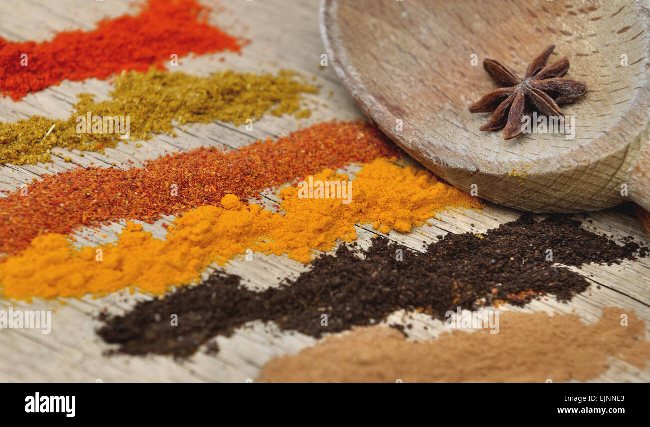 Bandes de différentes épices en poudre et une cuillère à l'anis sur fond de bois Banque D'Images