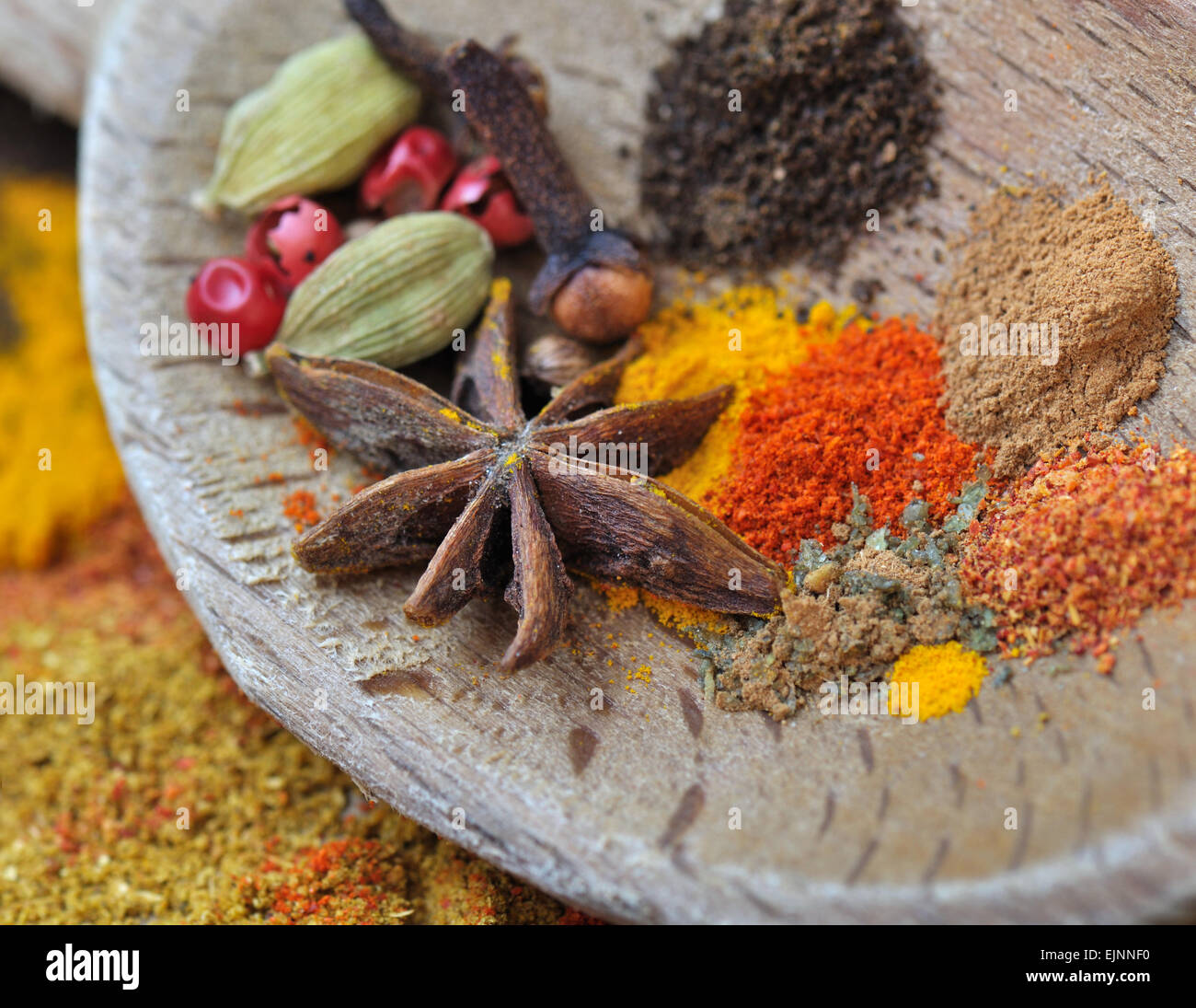 Épices colorées avec de l'anis dans une cuillère en bois Banque D'Images
