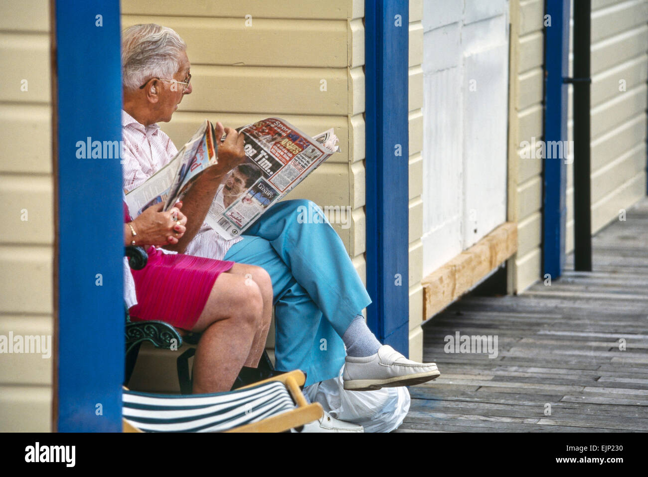 Une mature couple reading en regard de leur station beach chalet. Great Yarmouth. Le Norfolk. L'Angleterre. UK Banque D'Images