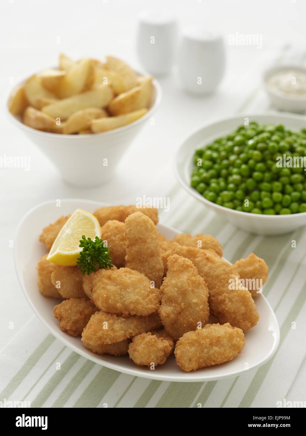 Goujons poisson pané, citron et le persil dans un bol plus de bols de peau sur 3,style rustique, petits pois, ramequins de sauce tartare Banque D'Images