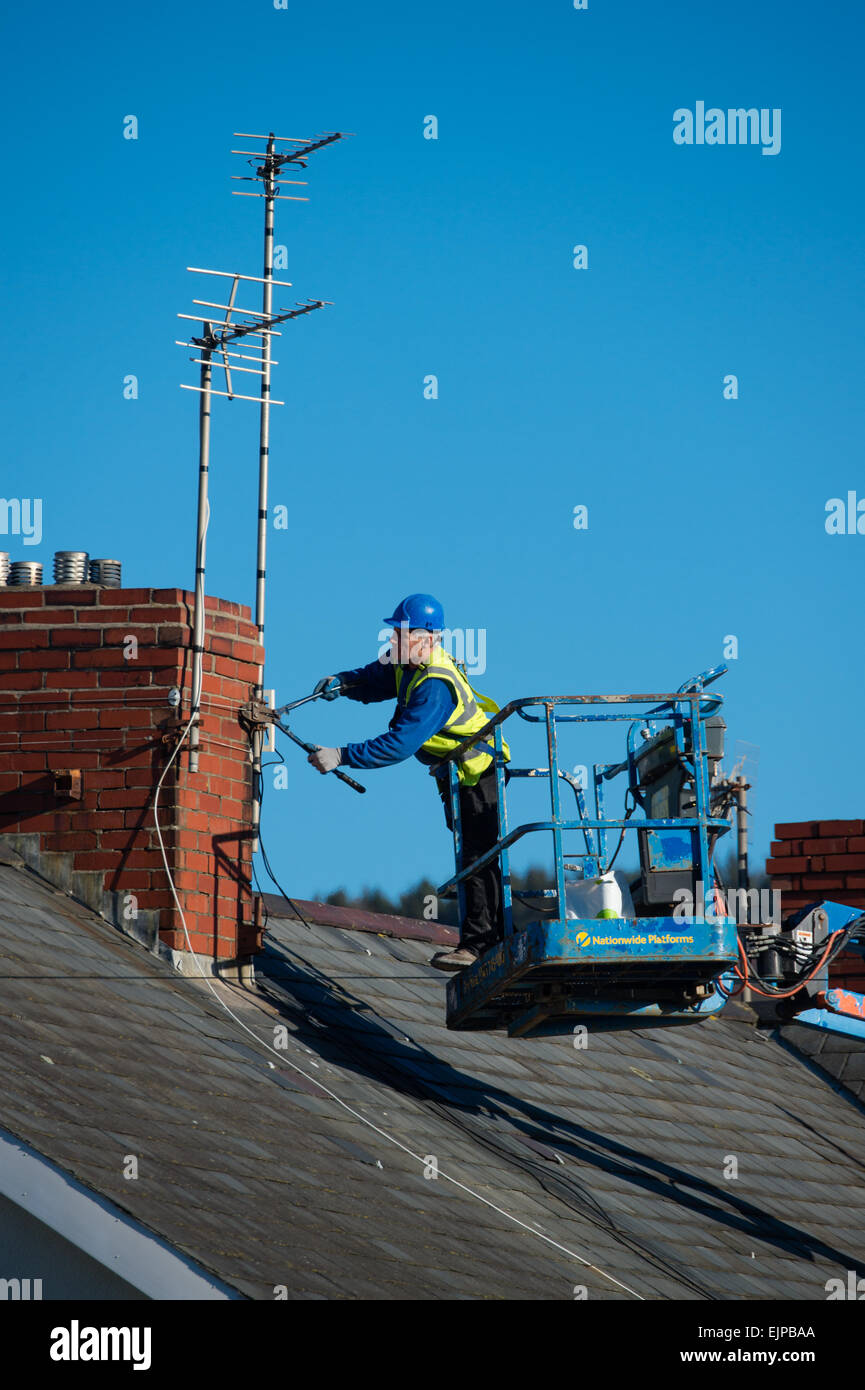 Un homme dans un harnais de sécurité et portent un casque travaillant dans  un 'grue' retrait de l'antenne de télévision d'une maison sur le point  d'être démoli UK Photo Stock - Alamy