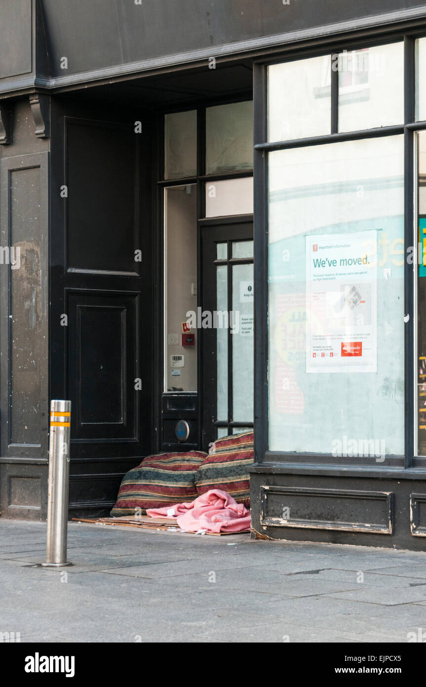 Coussins et couvertures utilisés par une personne sans-abri dans l'entrée d'un magasin désaffecté Banque D'Images