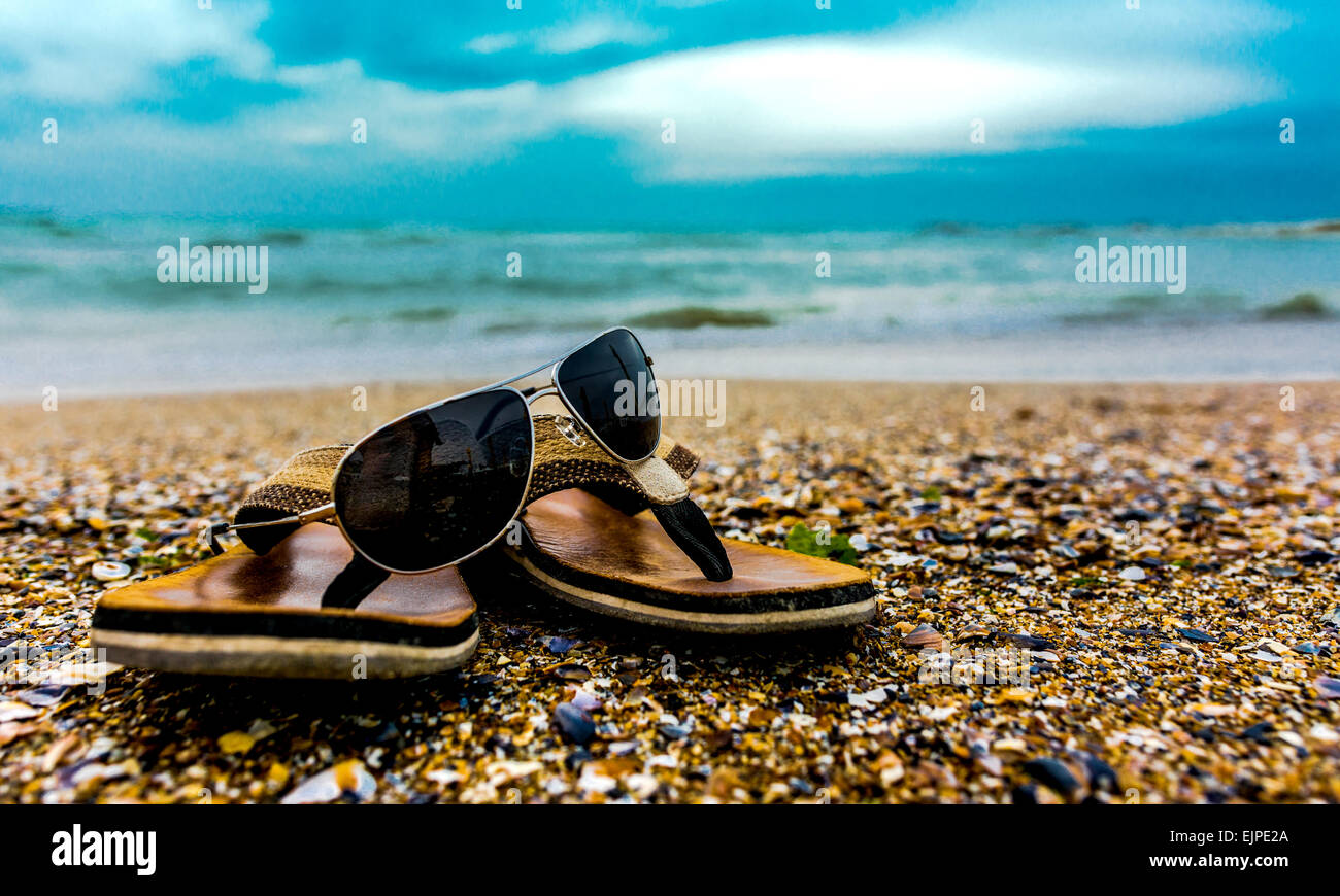 Des chaussons et des lunettes de soleil sur la côte de sable et l'eau de mer  Photo Stock - Alamy