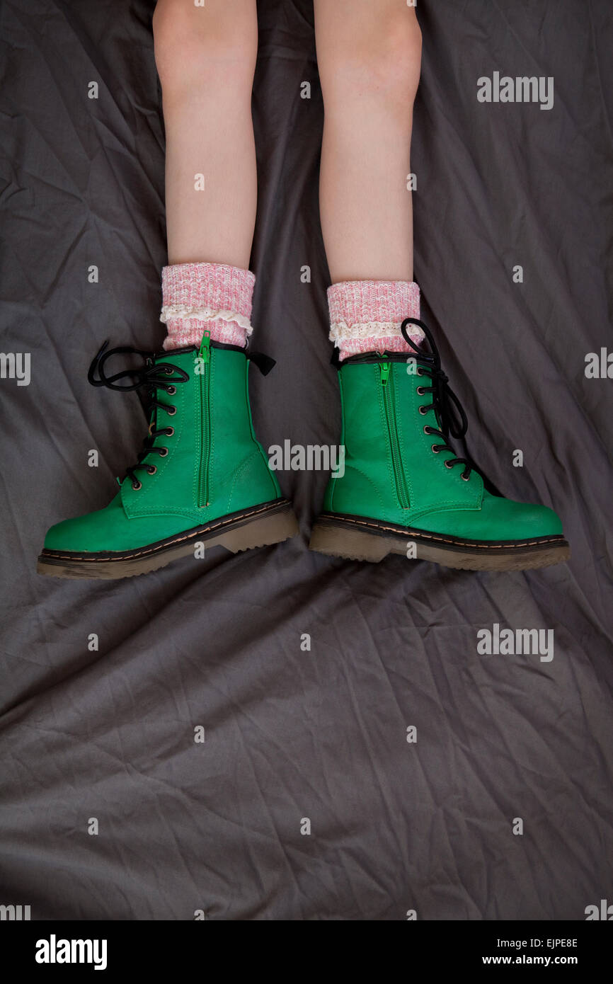 Girl in green Doc Marten bottes de style, couché sur un fond gris Banque D'Images