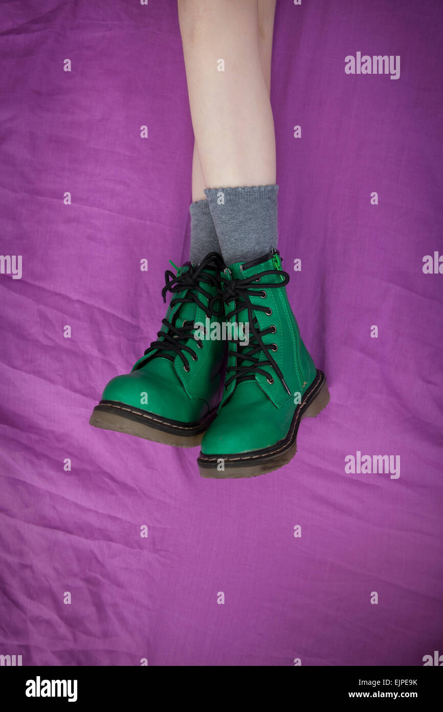 Girl in green Doc Marten bottes de style, couché sur fond violet Banque D'Images