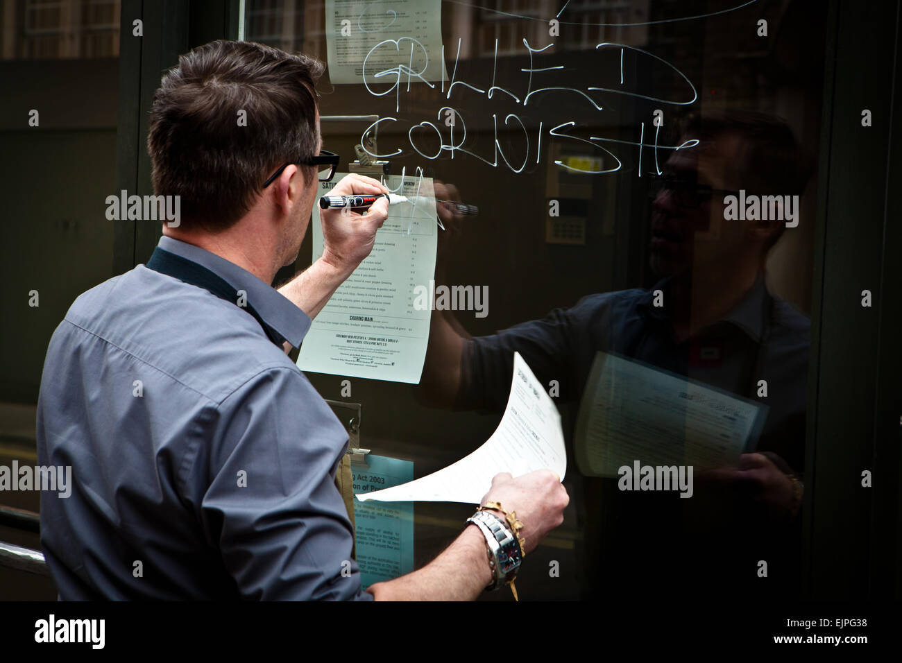 Menu restaurant Waiter writing sur fenêtre Banque D'Images