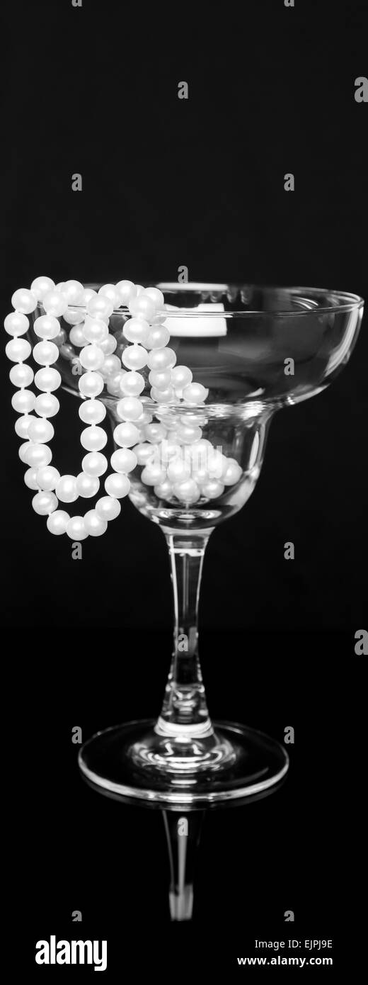 Un brin de belles perles s'asseoir à l'intérieur et s'enroulent sur le côté d'un verre de margarita ; noir et blanc sahara, vue panoramique Banque D'Images