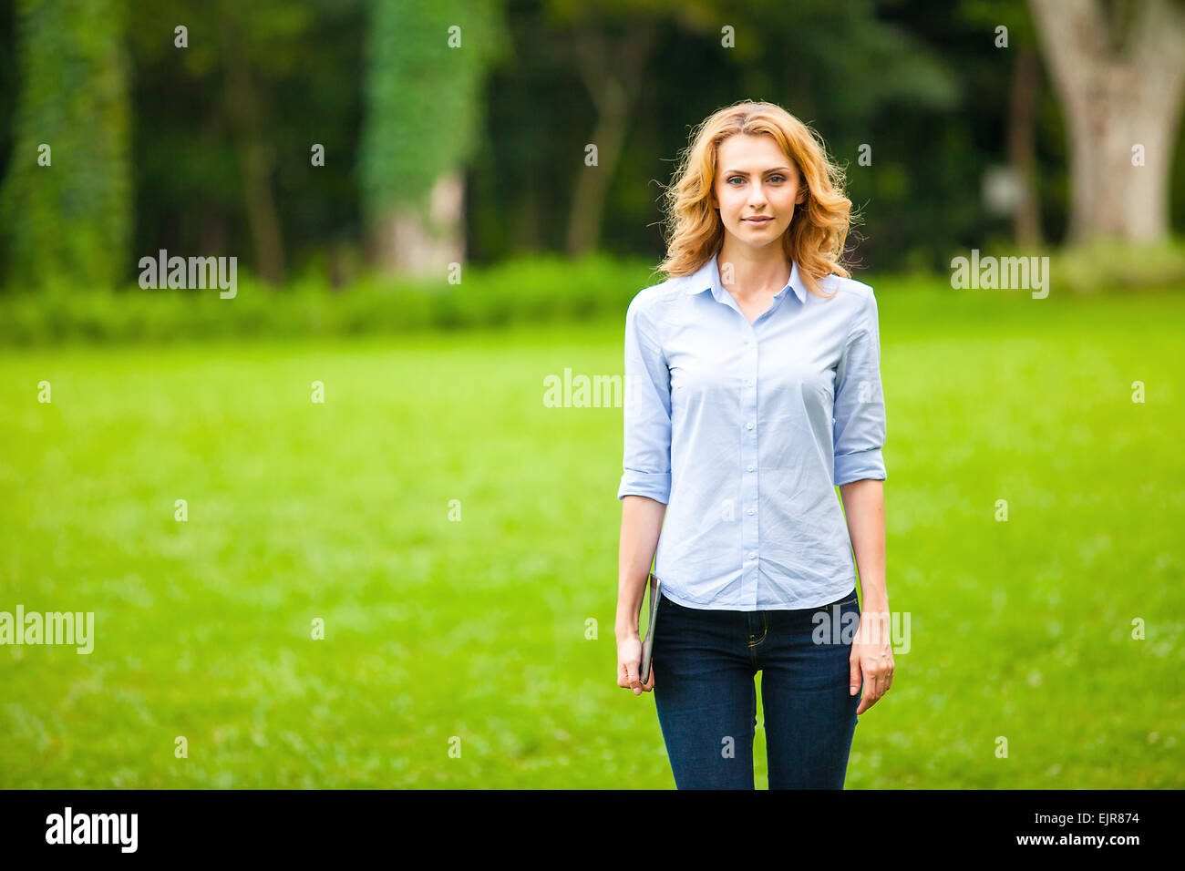 Belle jeune femme avec le comprimé dans la main, en marchant dans le parc Banque D'Images