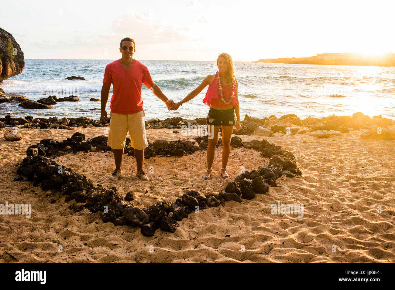 Couple holding hands in heart shape on beach Banque D'Images