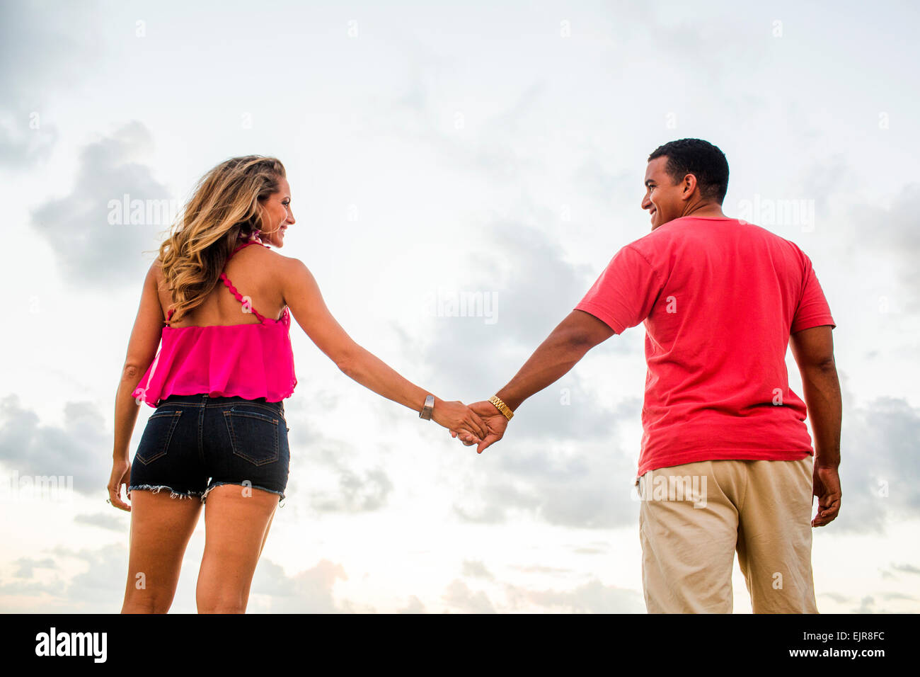 Low angle view of couple holding hands sous ciel nuageux Banque D'Images