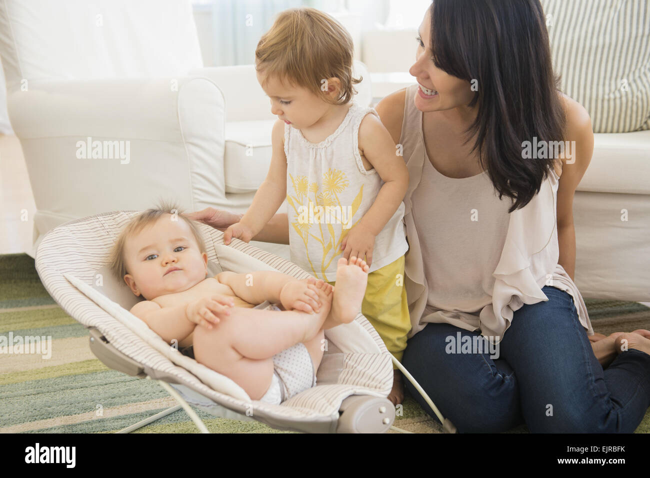 Mère et fille d'admirer bébé sur plancher du salon Banque D'Images