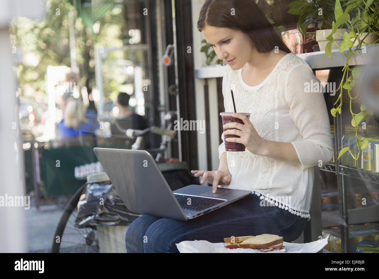 Caucasian woman using laptop et boire du café café à l'extérieur Banque D'Images