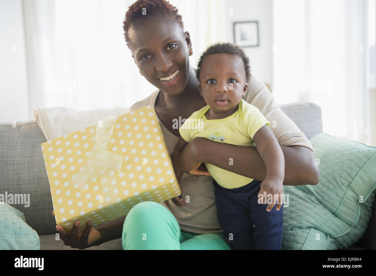 Mère noire et son holding gift on sofa Banque D'Images