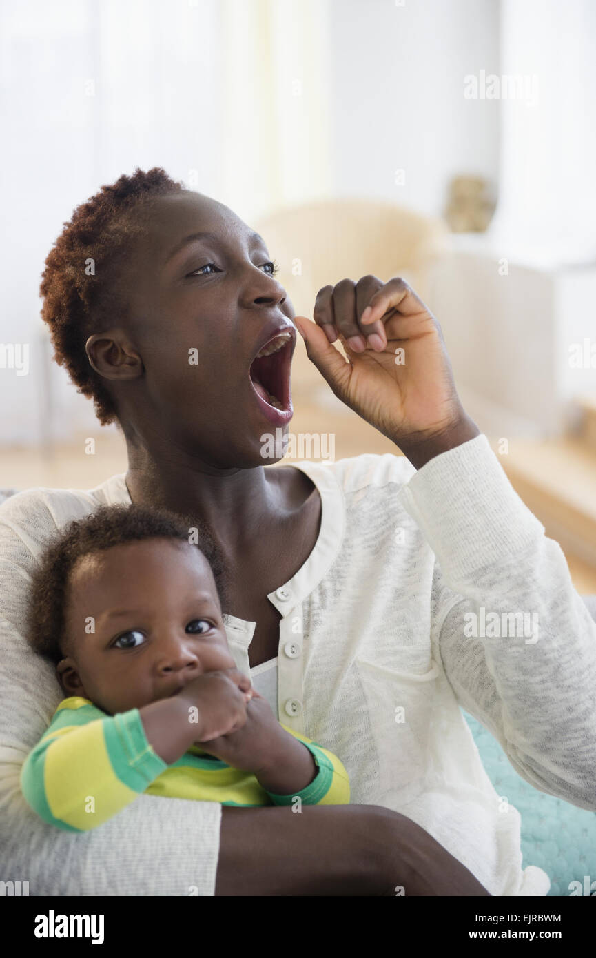Le bâillement Black Mother holding baby boy Banque D'Images