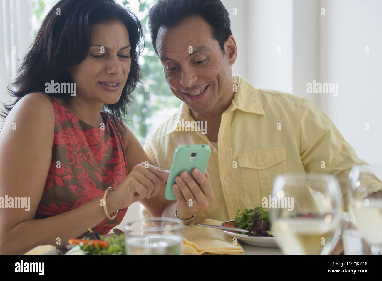 Couple using cell phone in restaurant Banque D'Images