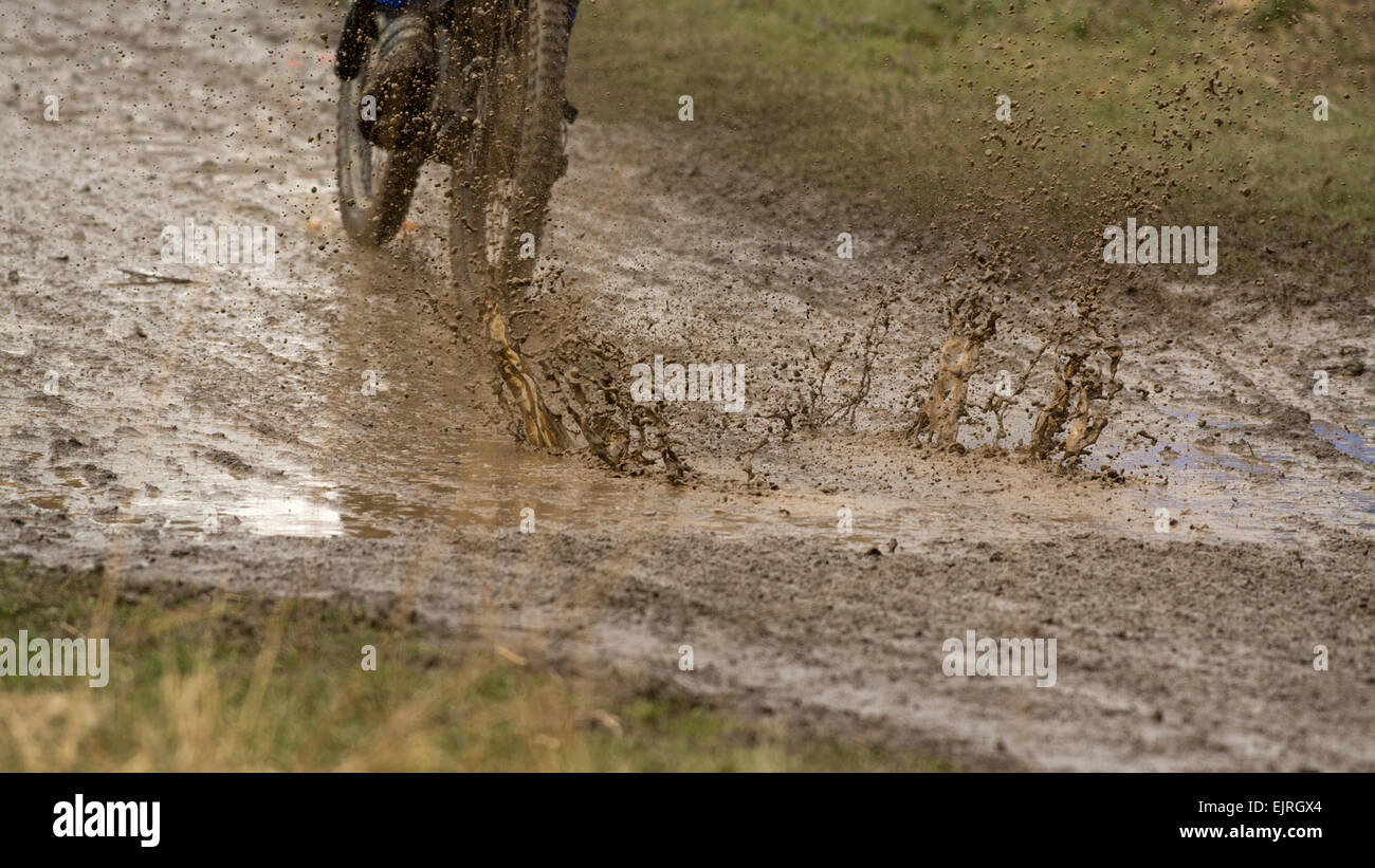 Circonscription cycliste vtt de descente éclaboussant par flaque d'eau très boueuses - Écosse, Royaume-Uni Banque D'Images