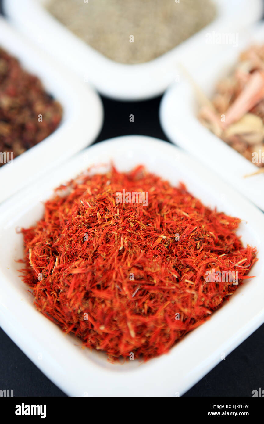 Le safran dans un petit plat blanc avec d'autres épices, qui tourne dans le sens horaire à partir du safran, poivre du Sichuan, les graines de cumin, la citronnelle Banque D'Images