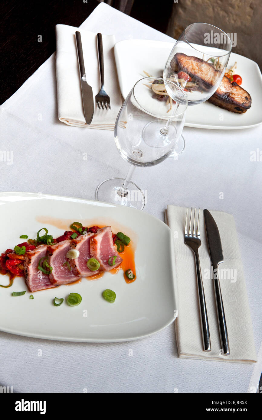 Des plats de poissons et de set de table sur une table dans un restaurant. Banque D'Images