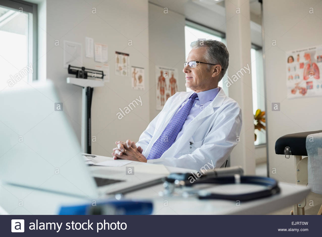Pensive doctor sitting at desk in office Banque D'Images