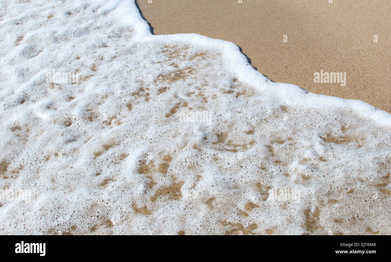 Mousse blanche de la vague de la mer sur la plage de sable Banque D'Images