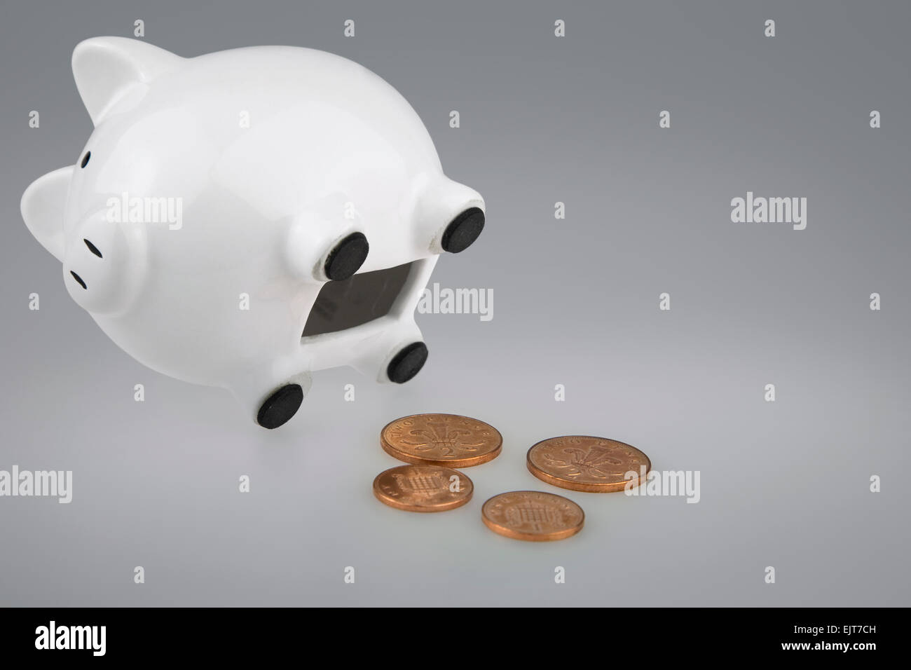 White Piggy Bank sur le côté avec fente de pièce ouvrir avec British deux pence et un pence coins sous Banque D'Images