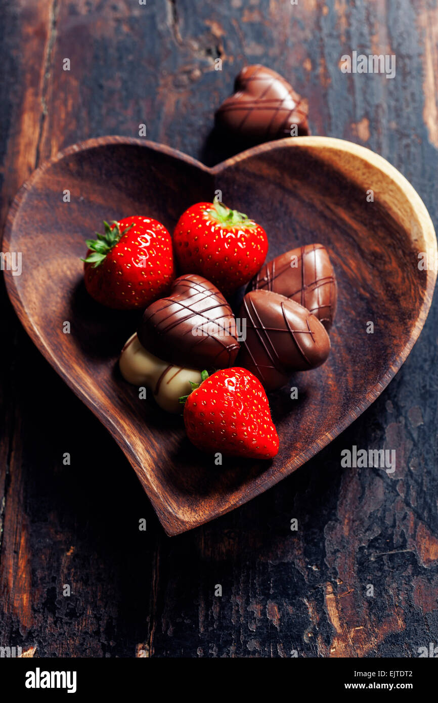 Plaque en forme de coeur avec des fraises et du chocolat sur table en bois - La Saint-Valentin et l'amour concept Banque D'Images