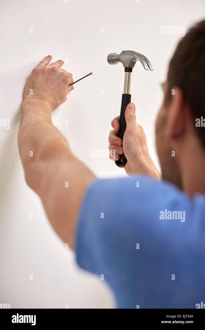 Close up of man with hammer hammering nail à wall Banque D'Images