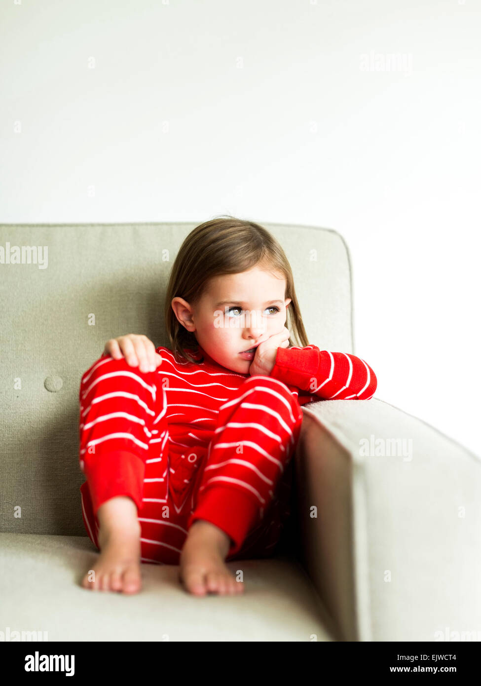 Girl (4-5) en pyjama sitting on sofa Banque D'Images
