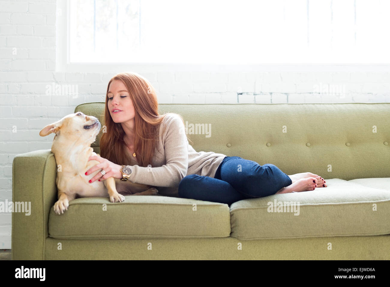Woman lying on sofa de caresser le PUG Banque D'Images