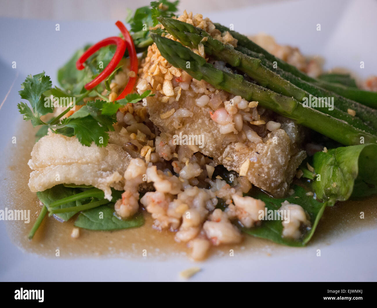 Aiglefin poêlé sauce à l'ail asperges épinards poisson plat asiatique Banque D'Images