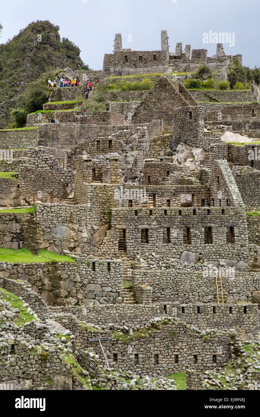 Le Pérou, Machu Picchu, reste de maisons dans l'ouest du secteur urbain. Les touristes en haut. Banque D'Images