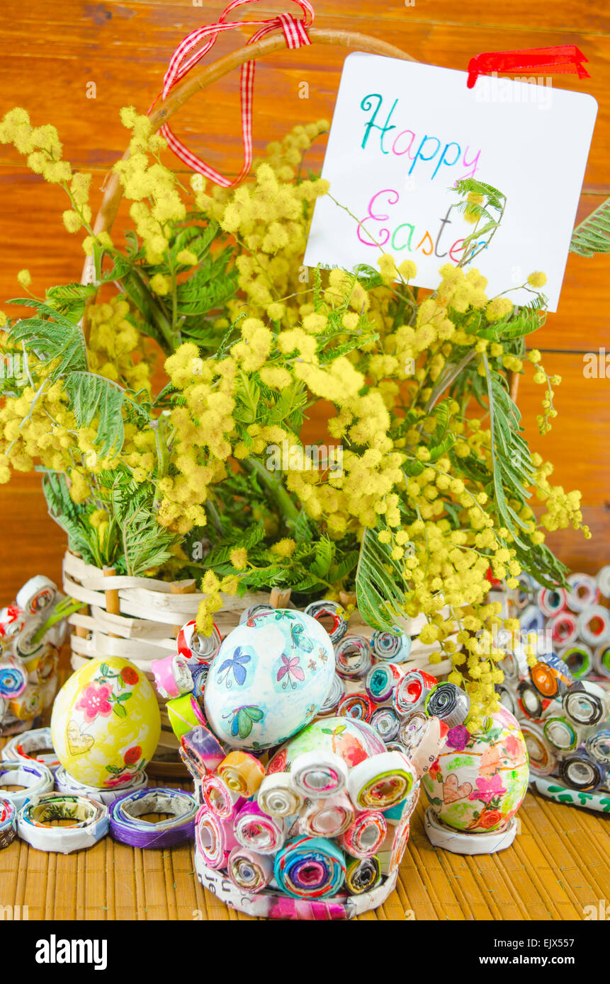 Papier fait main colorés avec des paniers remplis d'oeufs de Pâques et decoupage mimosa sur une table en bois Banque D'Images