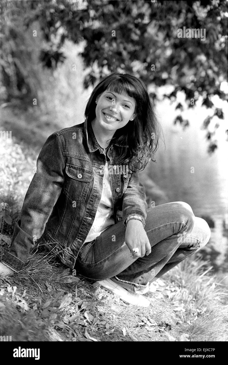 Young smiling woman sitting sur la rive du lac sous l'arbre. Banque D'Images