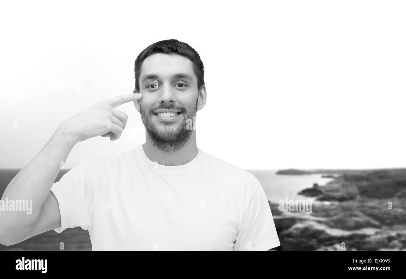 Smiling young man pointing pour les yeux Banque D'Images