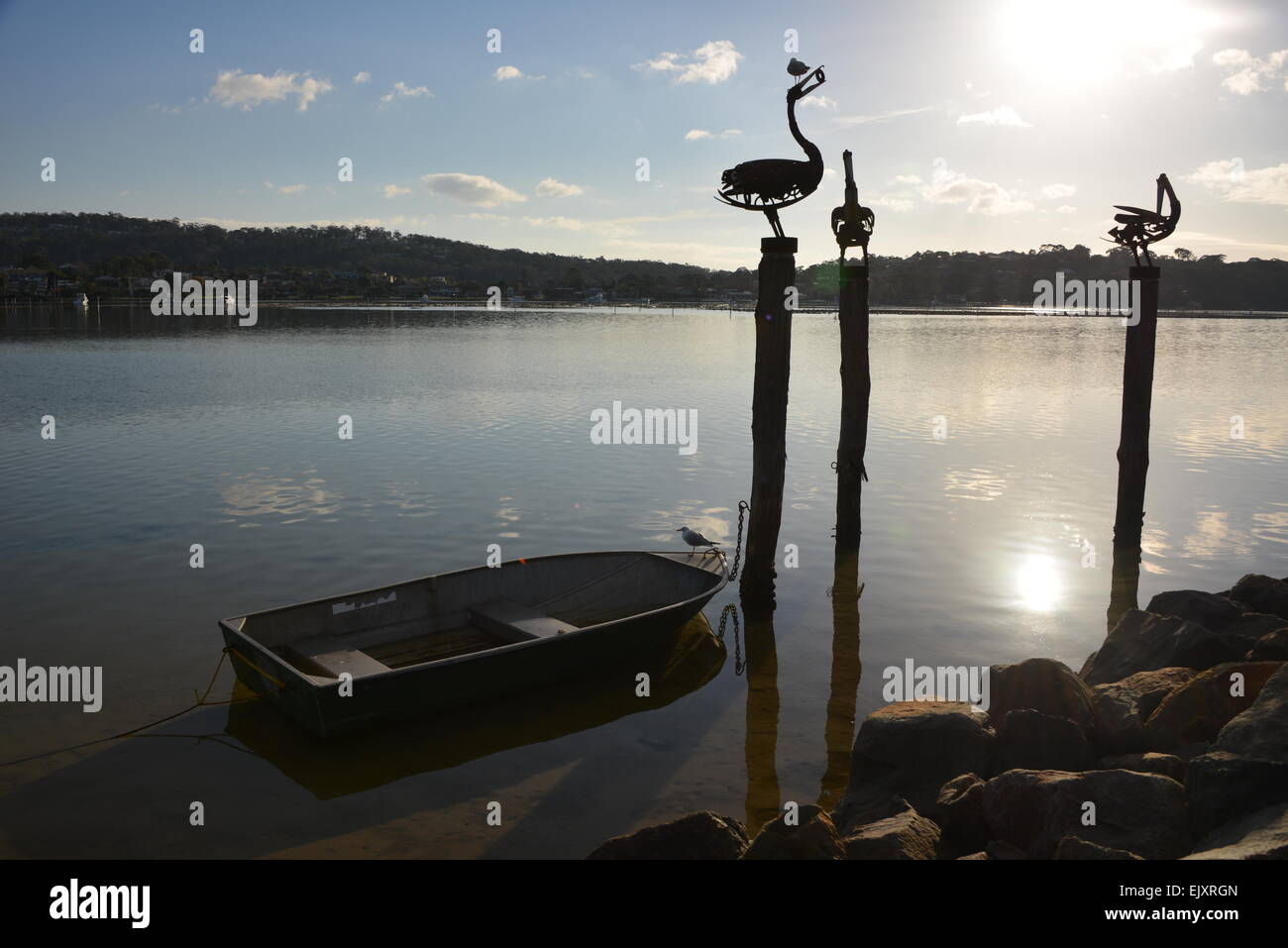 Ville côtière de pêche Merimbula NSW côte saphir lone bateau de pêche avec sculpture pelican donnant sur le lac et la ville Banque D'Images