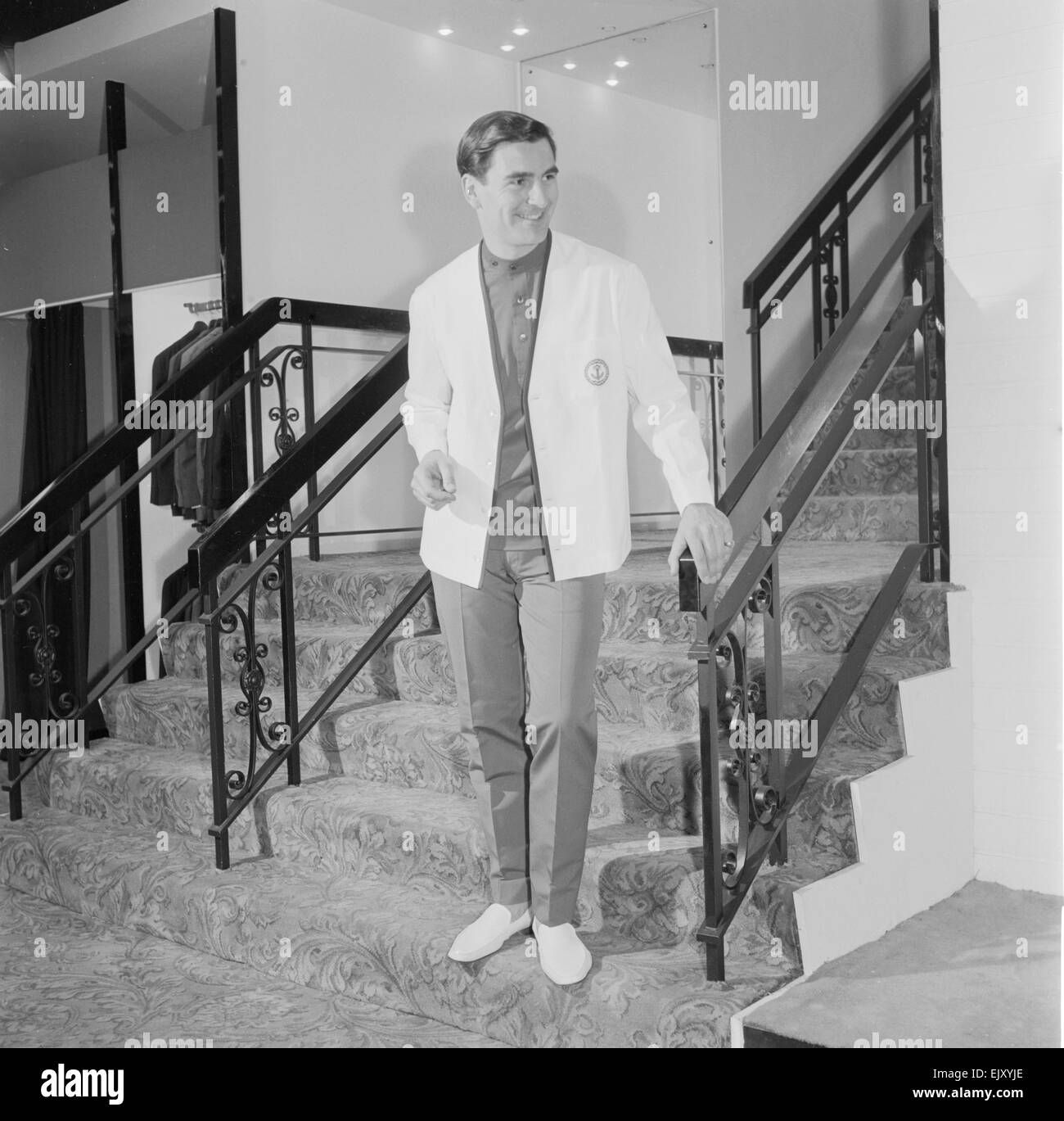 Le réveil la mode masculine de l'avenir tirer. Homme portant des vestes blanches dans les escaliers . Vers 1960 Banque D'Images
