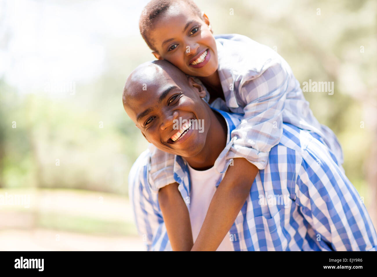 Pretty African woman piggyback ride on petit ami à l'extérieur Banque D'Images
