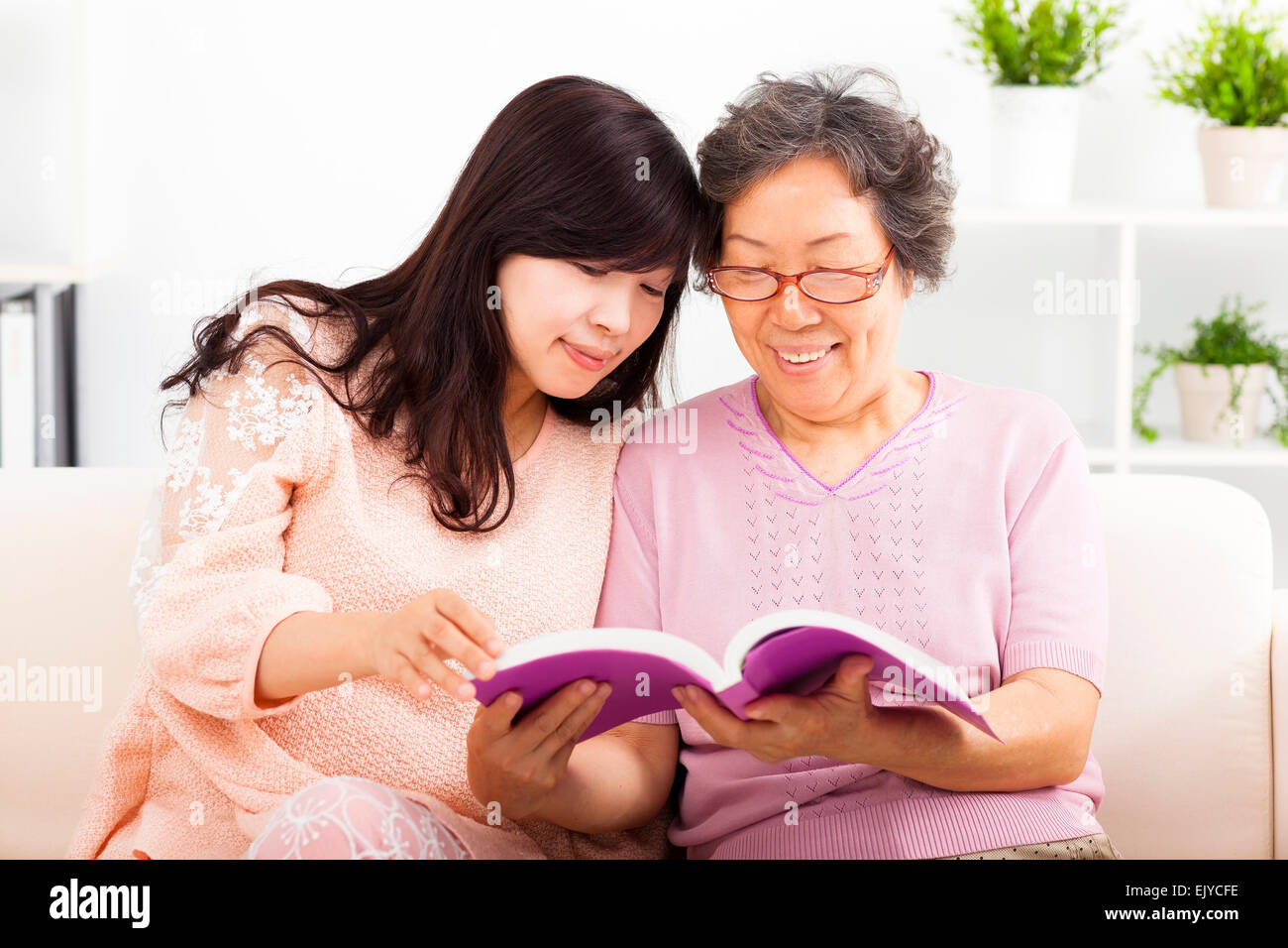 Happy mother and her daughter reading book Banque D'Images