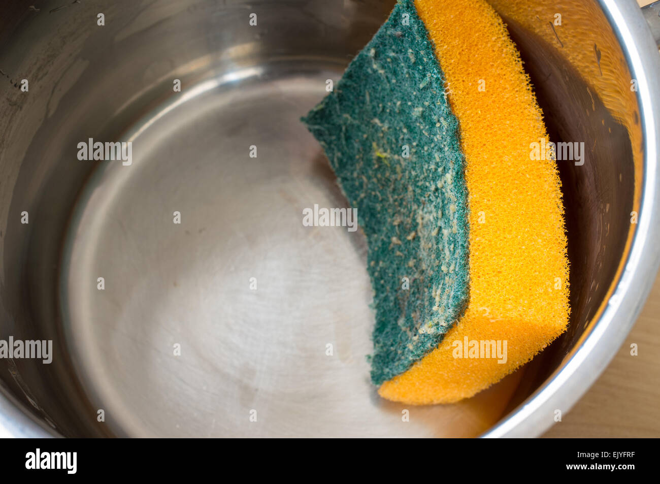 Laver à l'éponge après la cuisson casserole en acier sur une cuisine de restaurant Banque D'Images