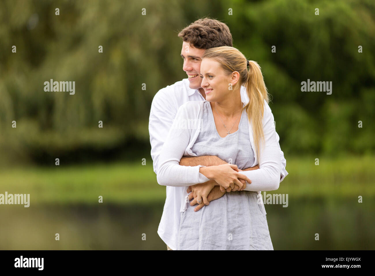 Jeune homme romantique hugging girlfriend outdoors Banque D'Images