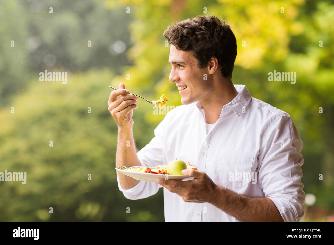 Beau jeune homme de manger des œufs brouillés pour le petit déjeuner Banque D'Images