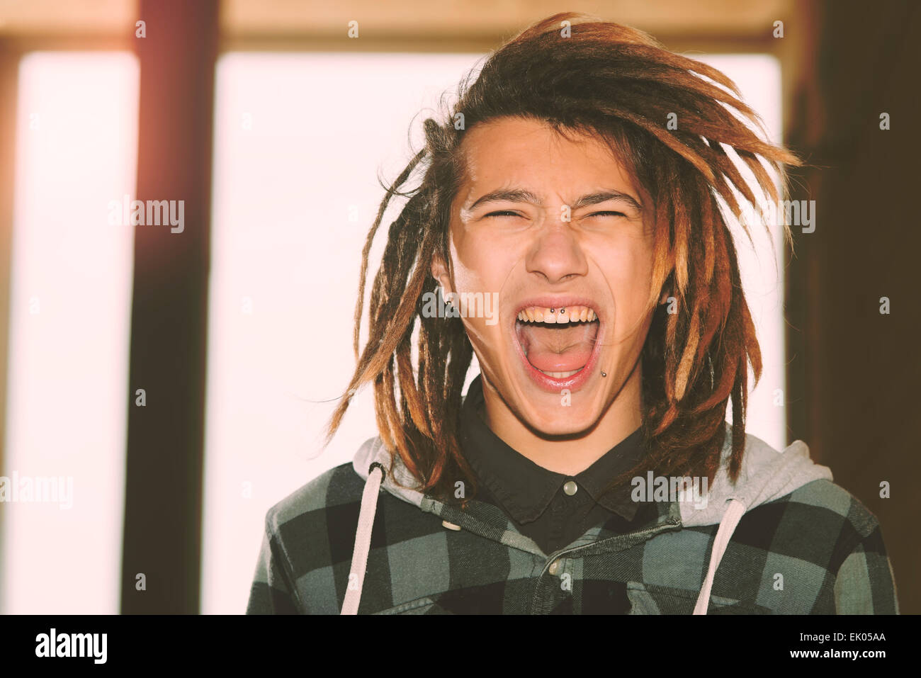 Portrait de jeune homme avec des cheveux rasta et skateboard dans un concept de vie filtre appliqué à chaud Banque D'Images