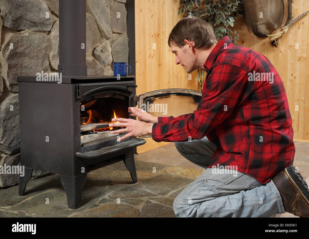 Bel homme rustique et réchauffement de la mains par cheminée cuisinière Banque D'Images