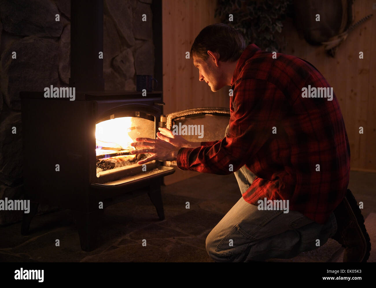 Bel homme rustique et réchauffement de la mains par cheminée cuisinière Banque D'Images