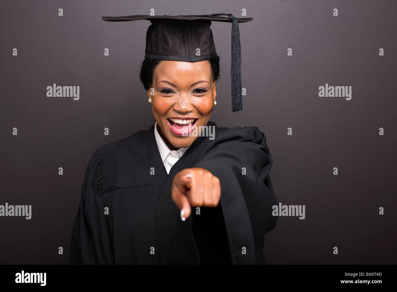 Female college graduate pointant isolé sur fond noir Banque D'Images