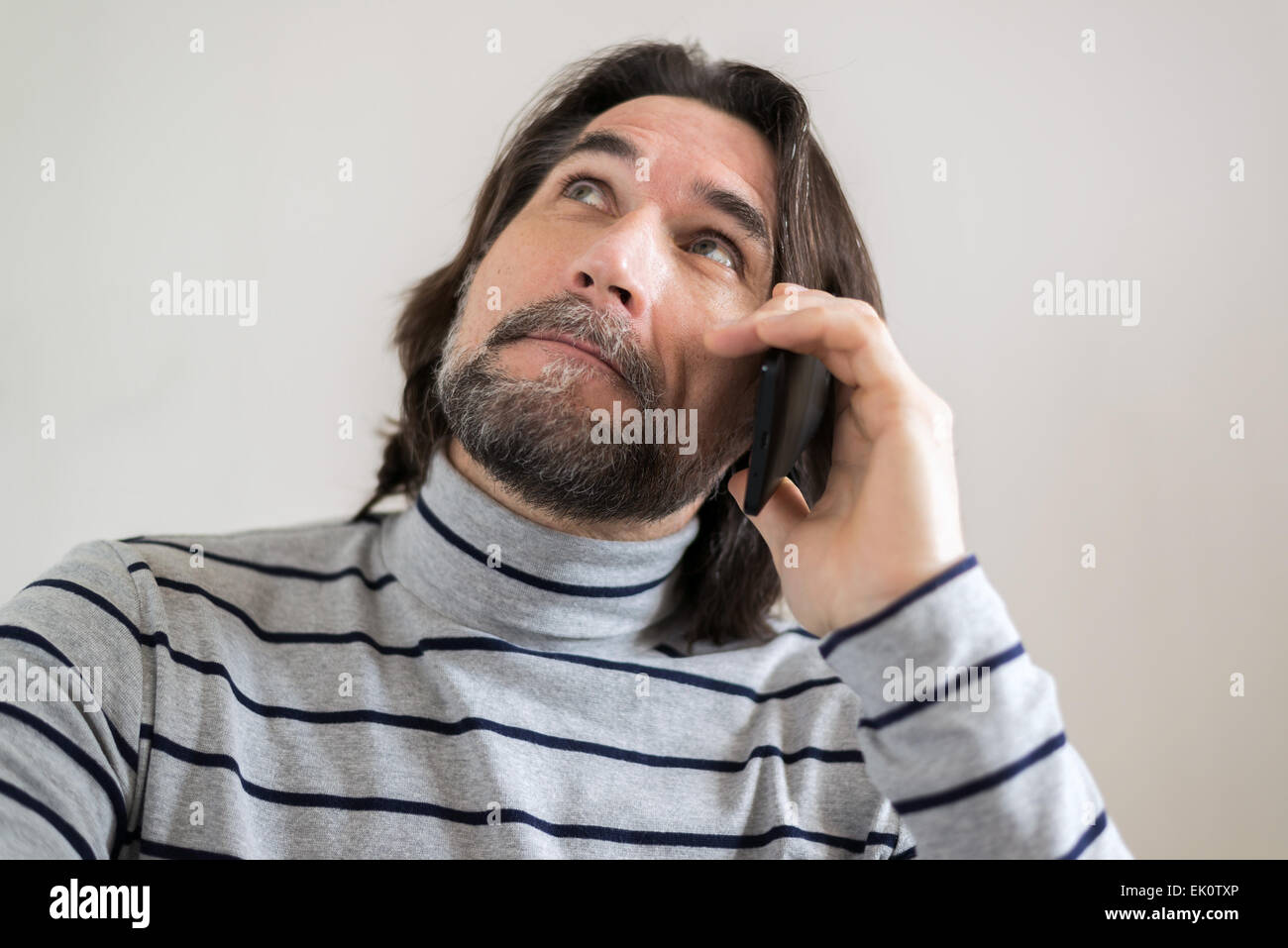 Homme barbu à parler au téléphone dans la salle de séjour Banque D'Images