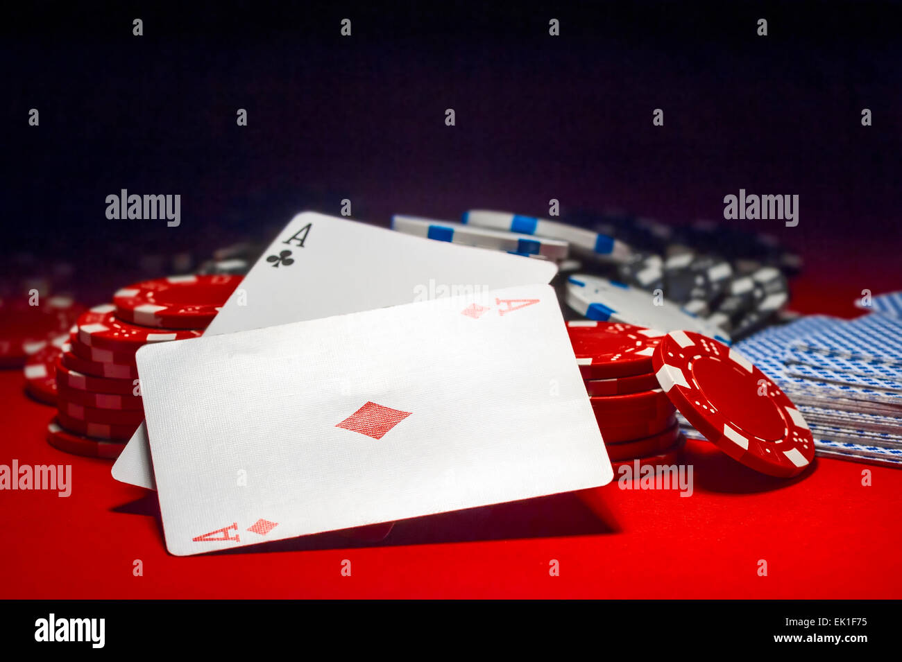 Deux as et une pile de jetons sur une table rouge Banque D'Images